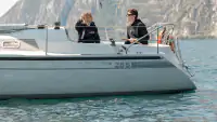 Two sailors on a sailing boat against the mountainous backdrop of Lake Garda
