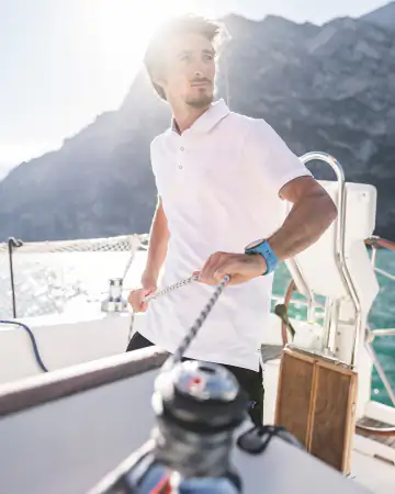 Segler beim Bedienen der Leinen an Bord eines Segelboots am Gardasee