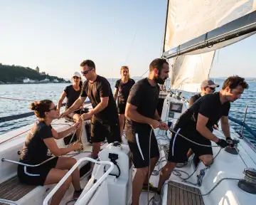 Team beim gemeinsamen Segelmanöver auf dem Gardasee
