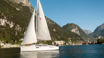 Segelboot unter vollen Segeln vor Riva del Garda und den Bergen