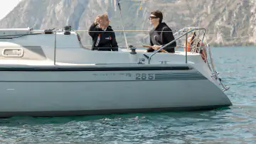 Zwei Segler auf einem Segelboot vor der Bergkulisse des Gardasees